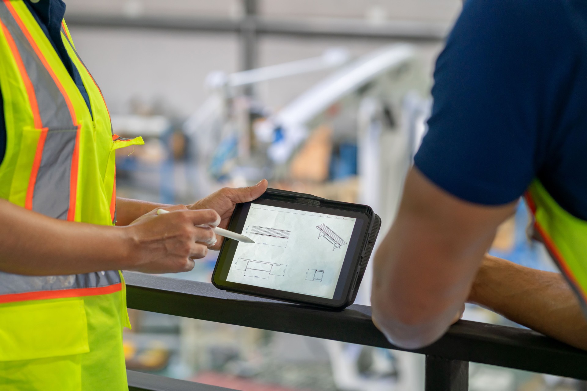 Close-up of a female engineer's hand explaining the structure of a robot arm being assembled on a production line using a digital tablet. Detailed analysis and teamwork involved in robotic assembly, emphasizing innovation, expertise, and quality control